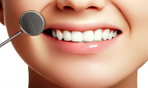 Close-up picture of a smiling happy woman with perfect teeth, showing her happiness with her All-on-Two implant-supported denture  she had made in Costa Rica.