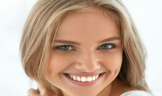 Picture of a woman, smiling at the camera, illustrating her happiness with the crown lengthening procedure she had in Costa Rica.