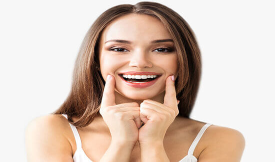 Picture of a woman, holding her two index fingers to the sides of her cheeks, illustrating her happiness with the dental implants she had in Costa Rica.