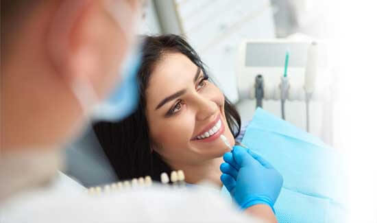 Picture of a woman sitting in a dental chair, smiling at the camera, illustrating her happiness with the oral surgery procedure she had in Costa Rica.