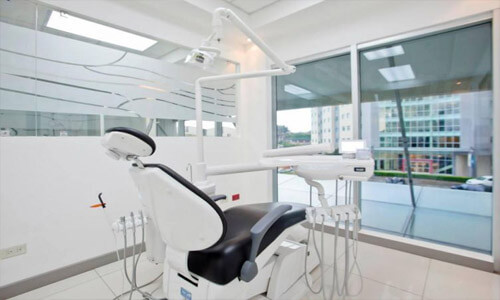 Picture of a dentist chair in a modern dental office.  The picture shows a white, modern and well-lighted interior.