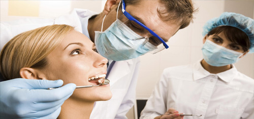 Picture of a happy female patient with long blonde hair having holistic dental work in Costa Rica.  The picture also shows a dentist and dental assistant.