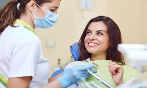 Close-up picture of a smiling woman with medium  brown hair, sitting in a dentist chair, and showing her perfect teeth, happy with the endodontics dental work she had done at Premier Holistic Dental in San Jose, Costa Rica.