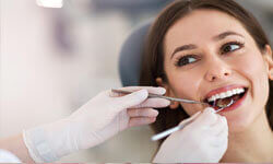 Picture of a smiling woman in a dental chair having an Endodontics dental treatment by Premier Holistic Dental in London.