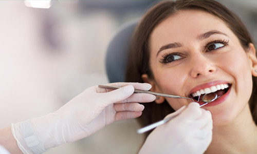 Close-up picture of a smiling young woman with long brown hair, sitting in a dental chair, happy with her Holistic dental treatment at Premier Holistic Dental in Costa Rica.