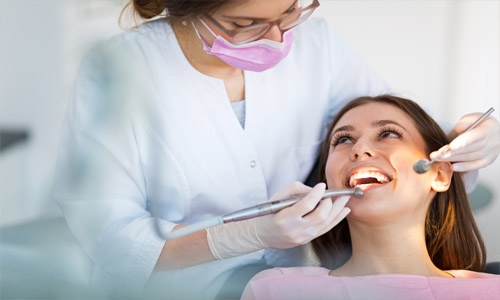 Close-up picture of a smiling young woman with long brown hair in a dental chair happy with her Holistic Huggins-Grube Protocol treatment at Premier Holistic Dental in Costa Rica.