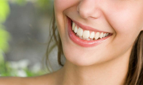 Close-up picture of a smiling woman with perfect teeth showing her happiness with the dental veneers she received at Premier Holistic Dental in Costa Rica.