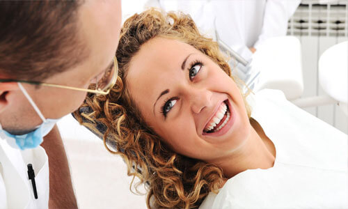 Close- picture of a happy woman with long curly brown hair, in a dental chair having a dental inlay/onlay procedure San Jose, Costa Rica.