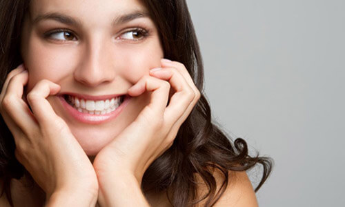 Close-up picture of a smiling young woman with long brown hair and perfect teeth, happy with her Holistic mercury free and fluoride free treatment at Premier Holistic Dental in Costa Rica.
