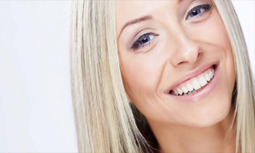 Close-up picture of a smiling woman with long blonde hair, showing her perfect teeth, and happy with the periodontics dental work she had done at Premier Holistic Dental in San Jose, Costa Rica.