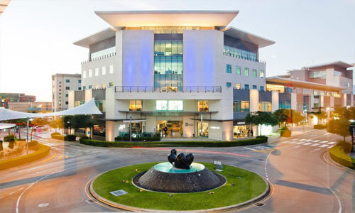 Picture of a 5 story office building in Costa Rica.  A traffic circle is shown in the picture in front of the building