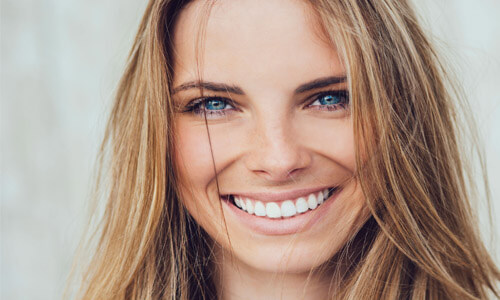 Close-up picture of a smiling young woman with long sandy brown hair, happy with her Platelet Rich Plasma (PRP) treatment at Premier Holistic Dental in Costa Rica.