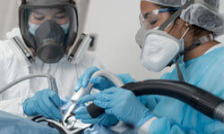 Picture of two dentists wearing protective equipment performing a Holistic dental procedure in Costa Rica.  The dentists are wearing a state-of-the-art protective garment, masks and gloves.