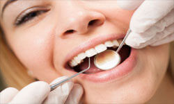 Picture of a smiling woman in a dentist chair having a teeth cleaning procedures by Premier Holistic Dental in London.