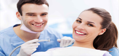 Picture of a smiling patient in a dental chair and having holistic dental work in Costa Rica. The picture also shows a dentist and dental assistant in white coats.